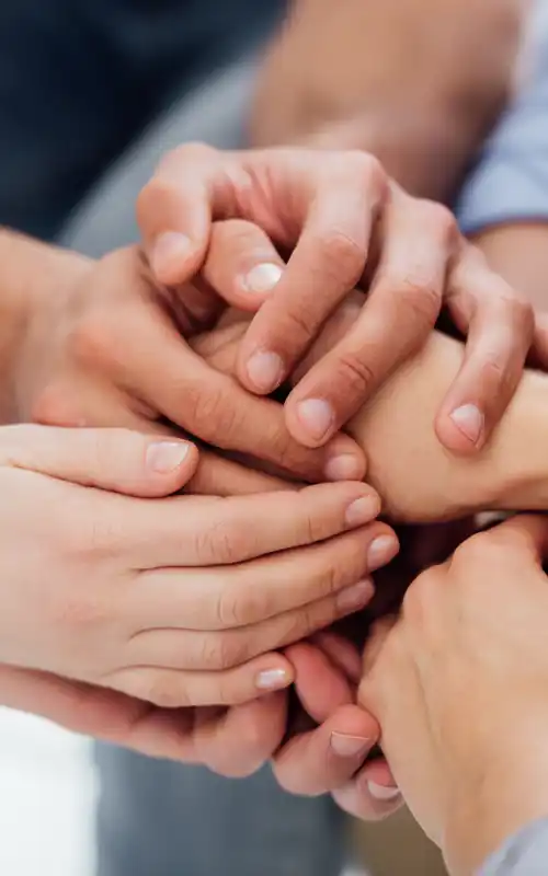 A group of diverse hands clasping together in support