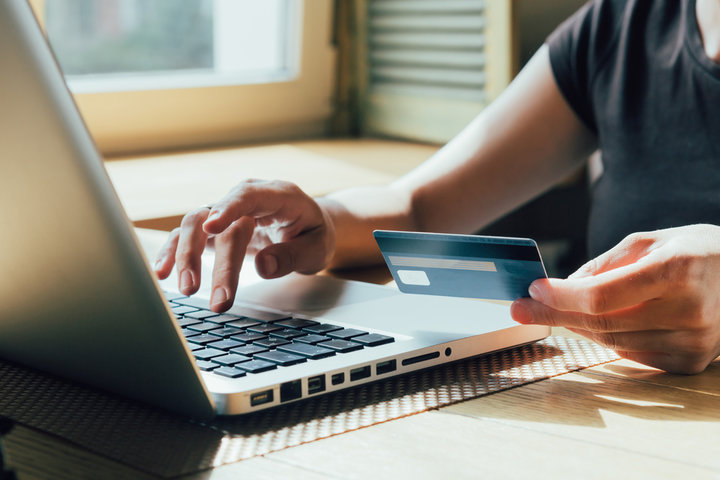 man holding credit card while typing at computer