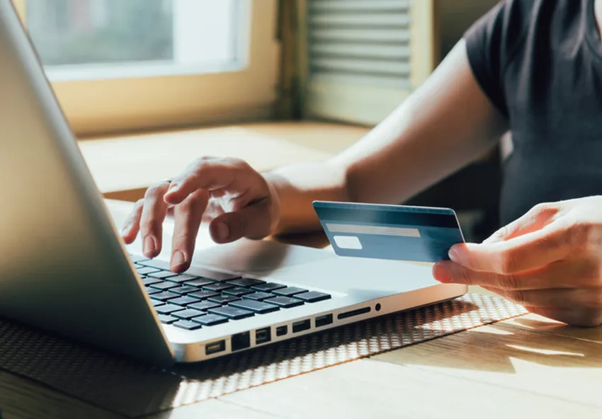 man holding credit card while typing at computer