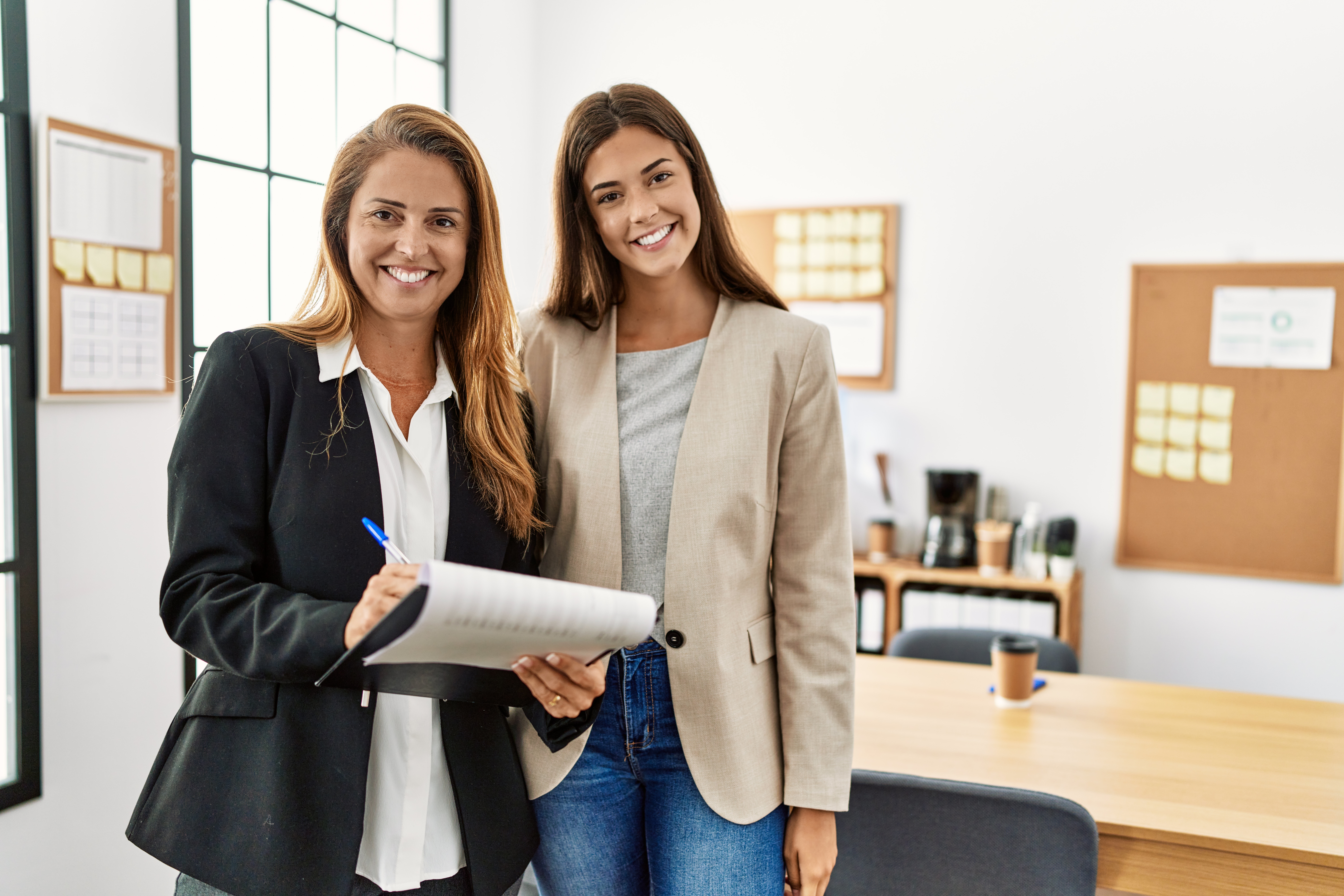 An older woman in a suit standing next to a younger woman smiling