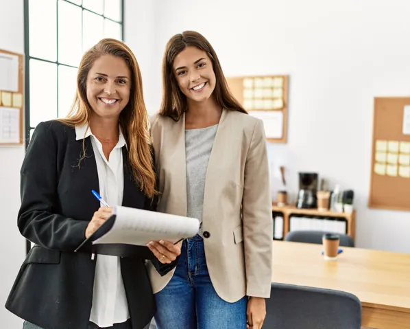 An older woman in a suit standing next to a younger woman smiling