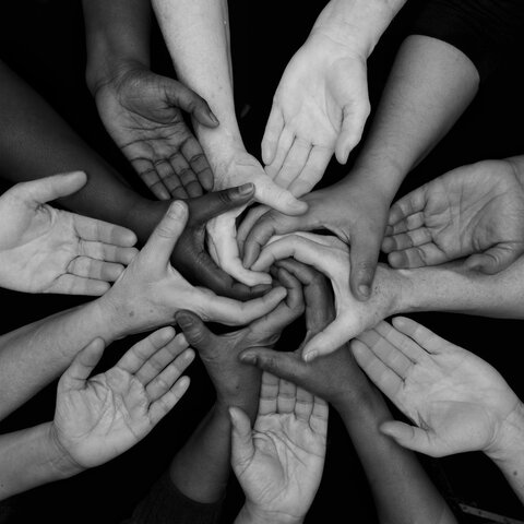 A group of diverse hands clasping together in support