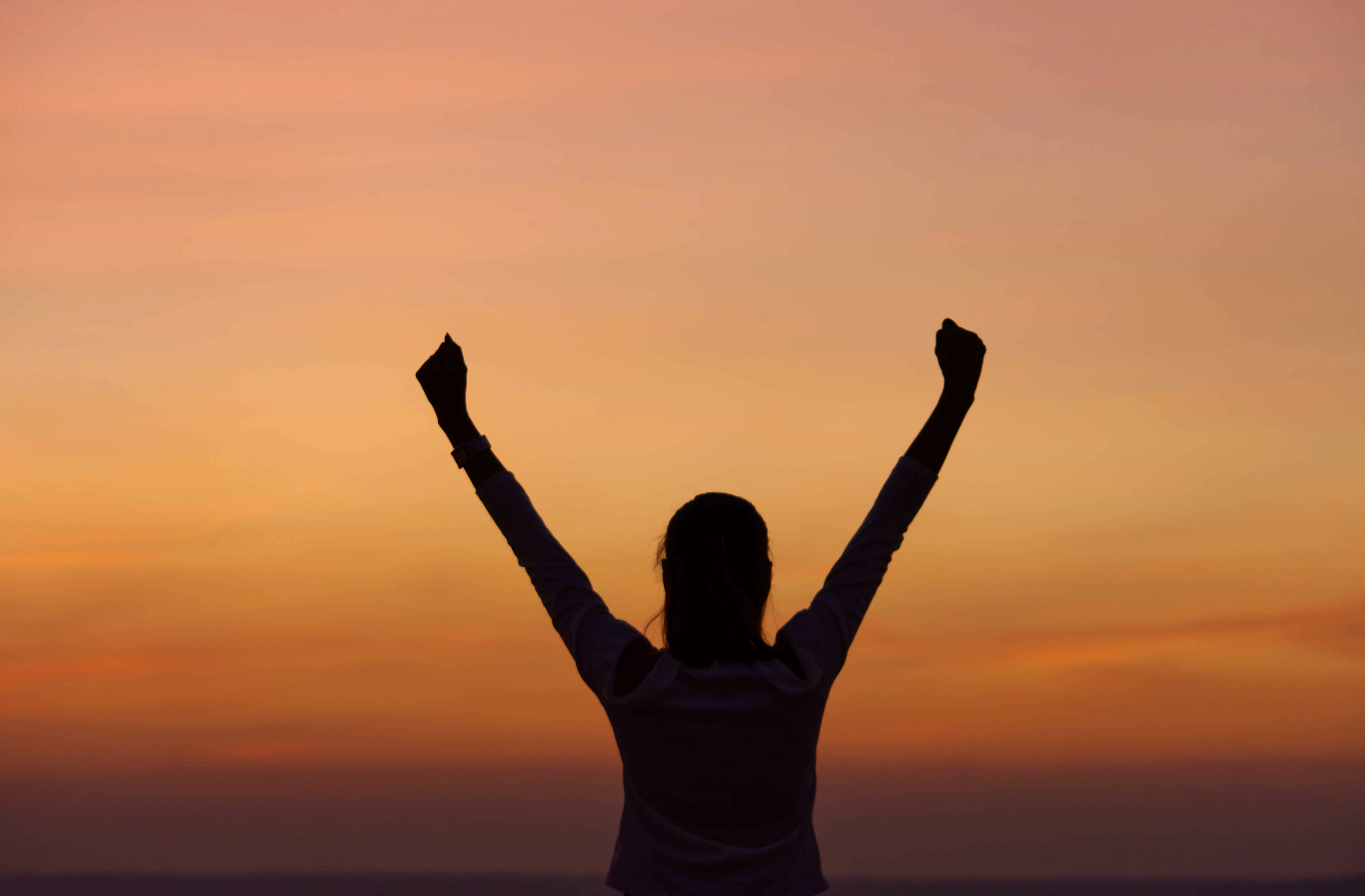 A woman outstretching her hands in the sunset light