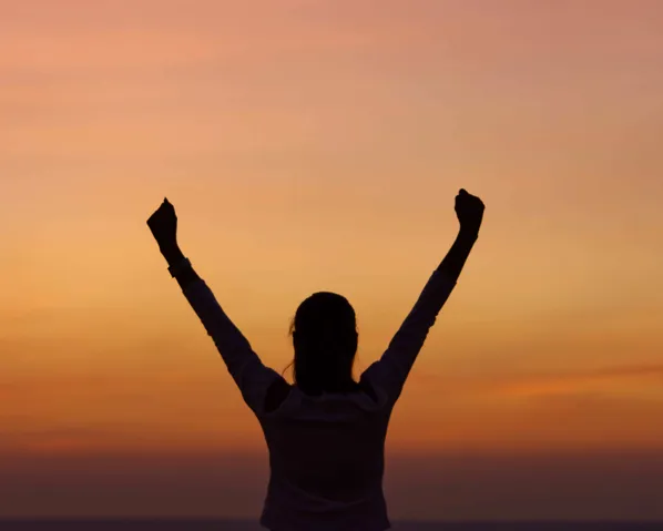 A woman outstretching her hands in the sunset light