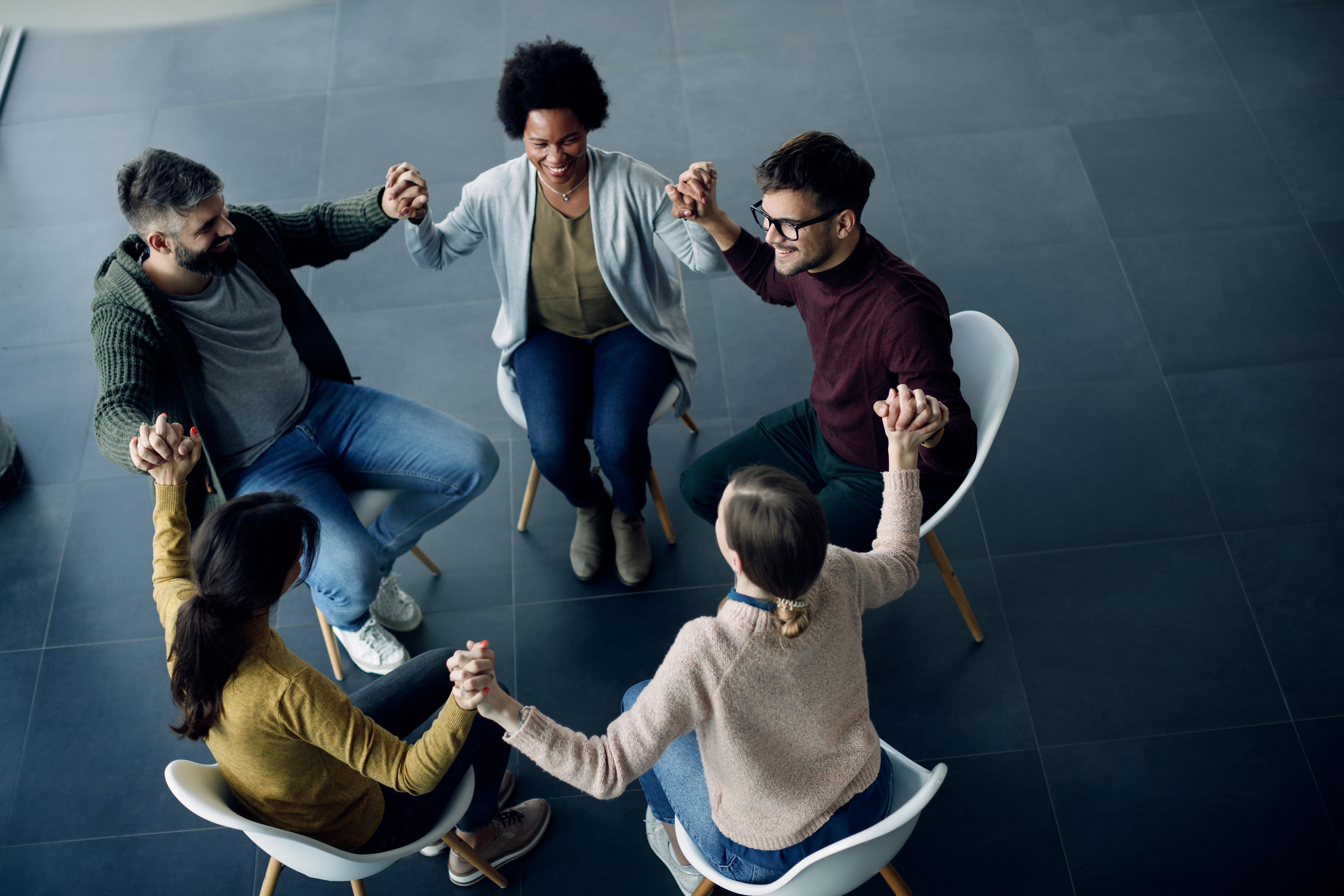 A therapy group holding hands and raising their arms together in support