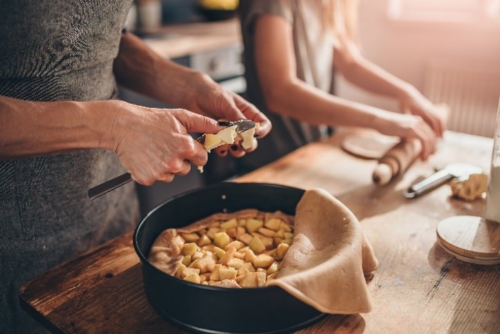Two people peeling potatoes into a pot in a cozy setting