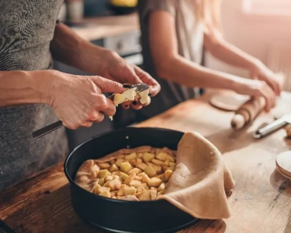 Two people peeling potatoes into a pot in a cozy setting