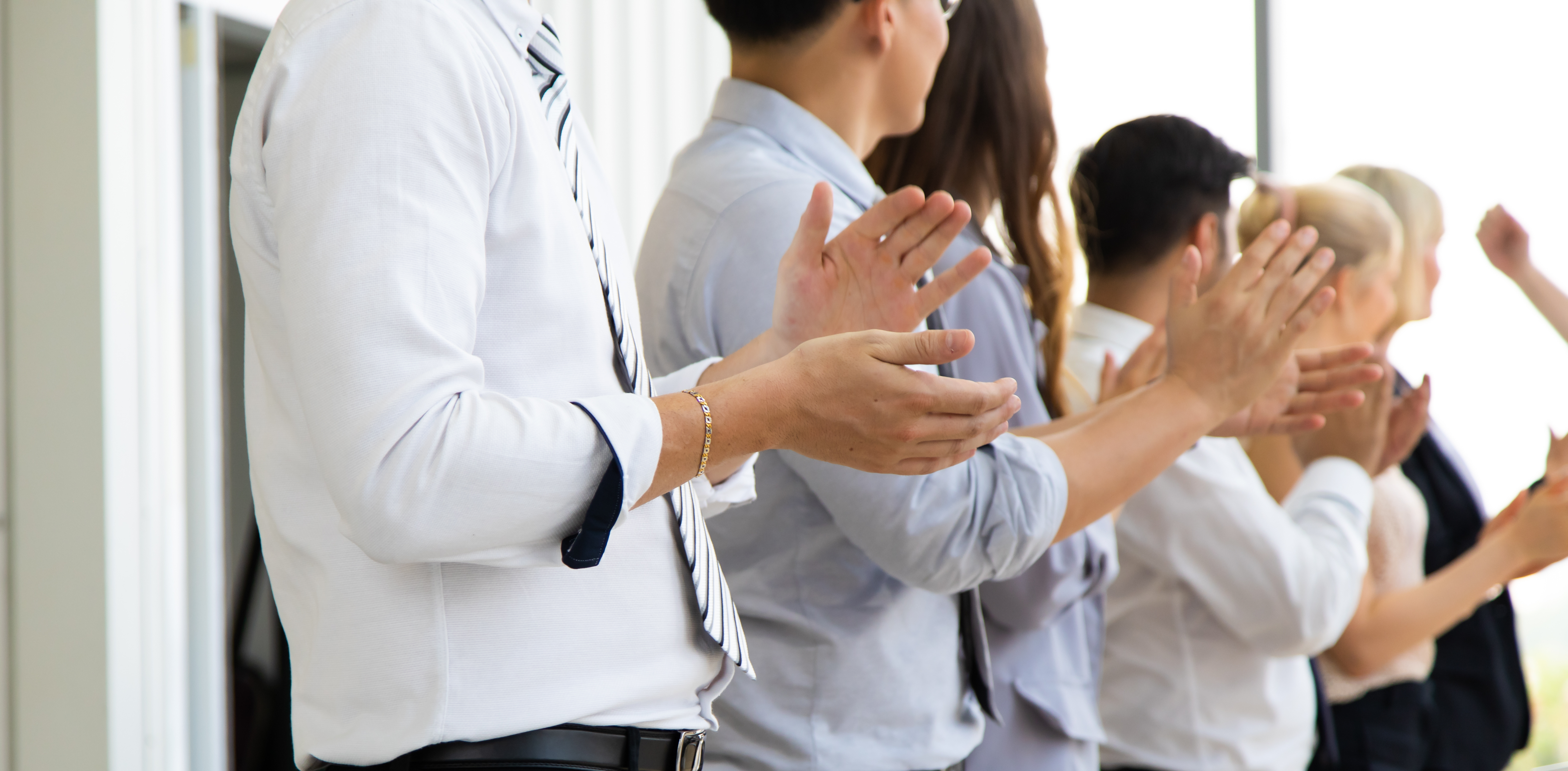 A group of employees clapping their hands together in approval