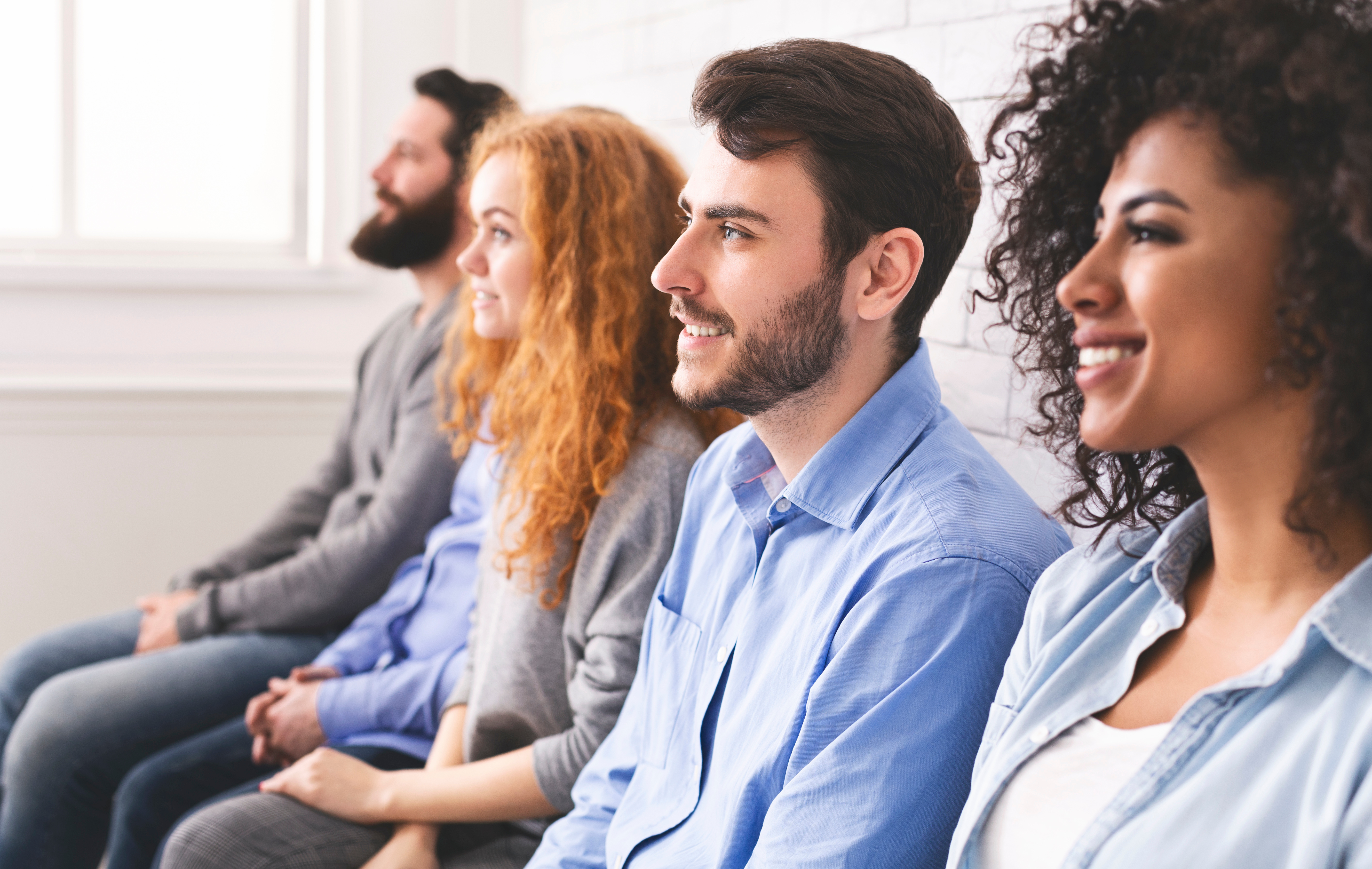 Two men and two women sitting and smiling in the same direction