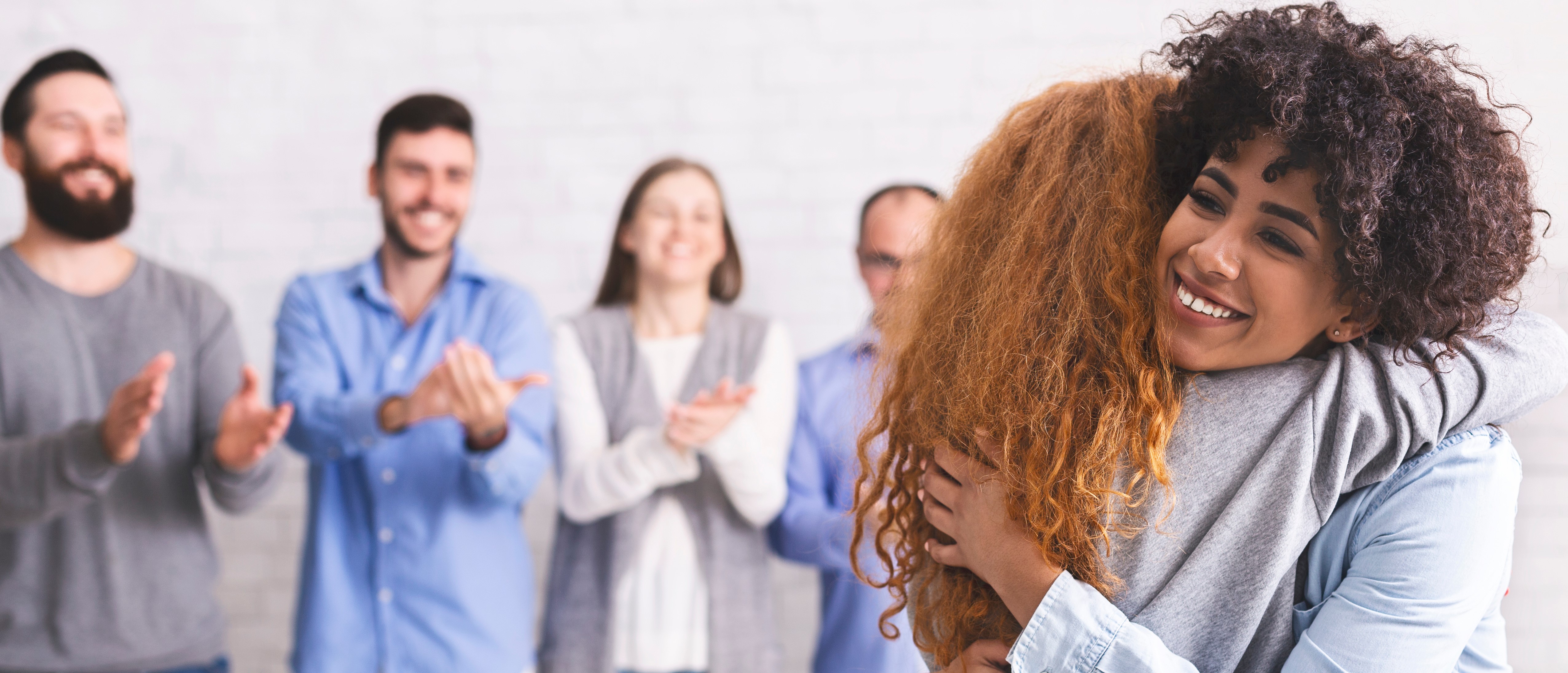 A red headed girl hugging a curly headed girl