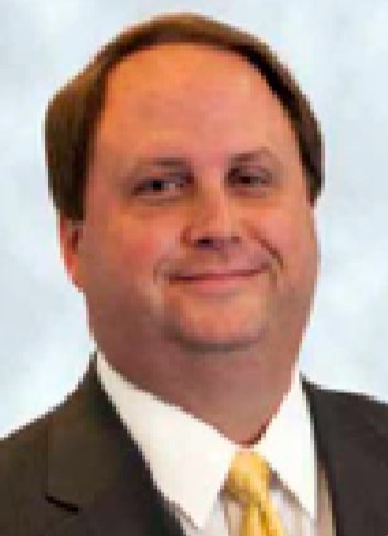 David A Coe man with short hair cut in a suit with yellow tie