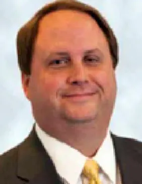 David A Coe man with short hair cut in a suit with yellow tie