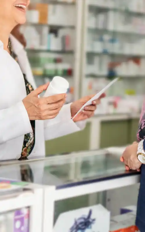 A pharmacist smiling and exchanging a bottle to a patient.
