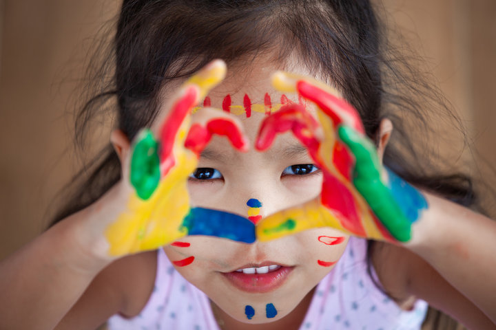 A child with colorful painted hands shaped in a heart
