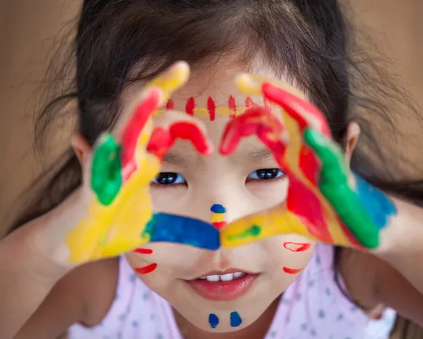 A child with colorful painted hands shaped in a heart