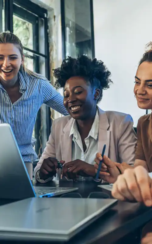 A group of interns around a laptop in a meeting smiling