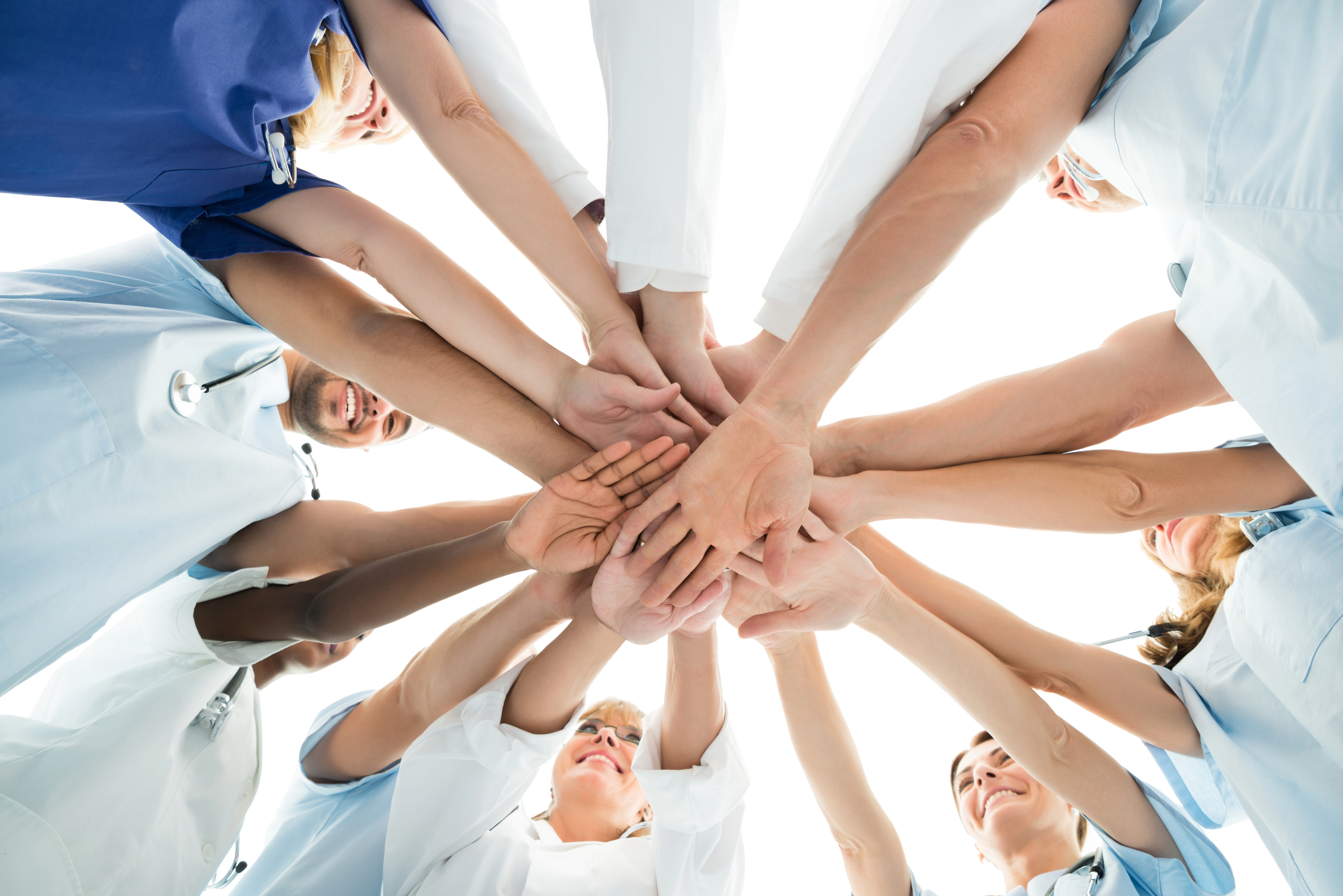 A group of people in light blue shirts extending their hands together