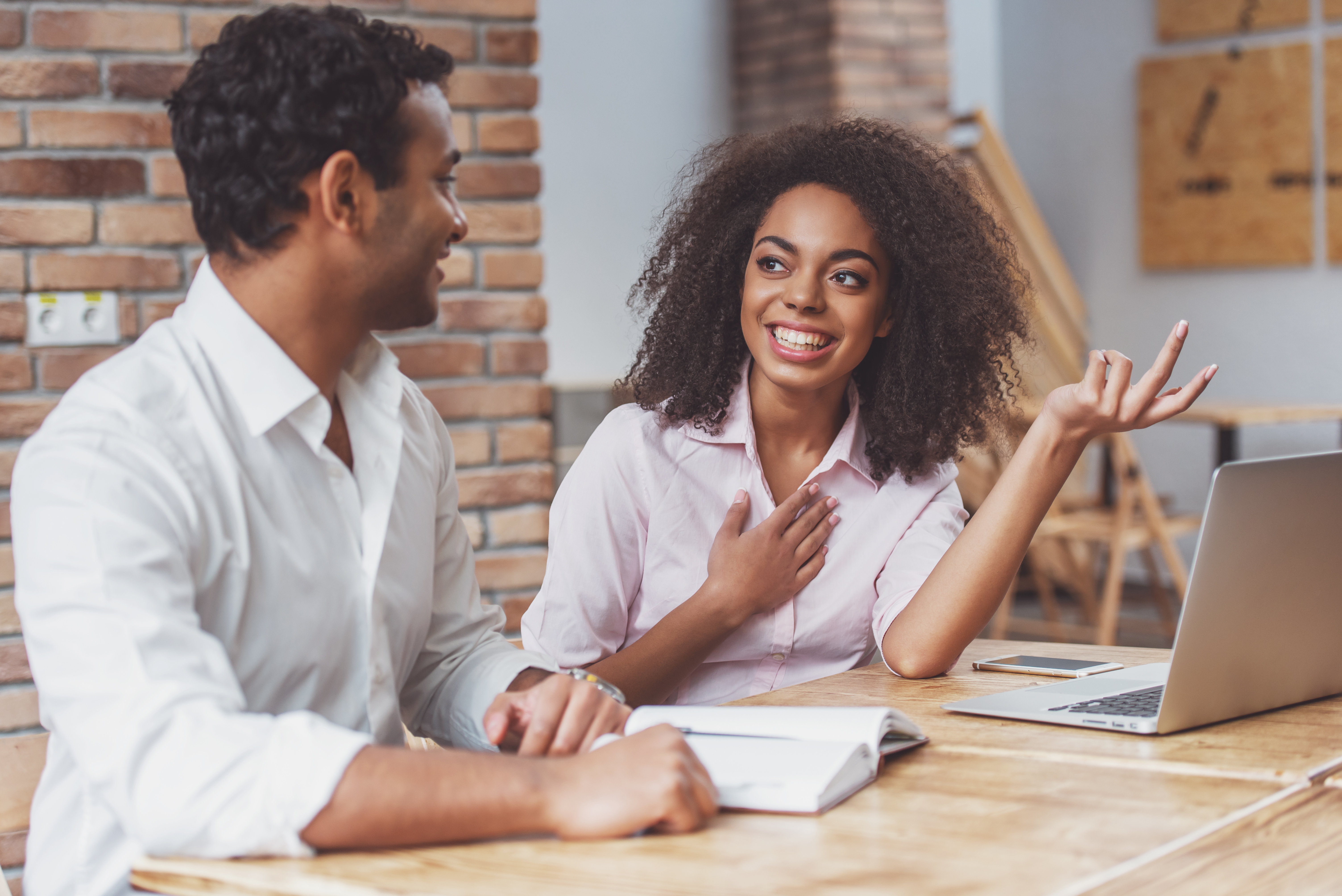 man and woman sitting at table laughing and smiling