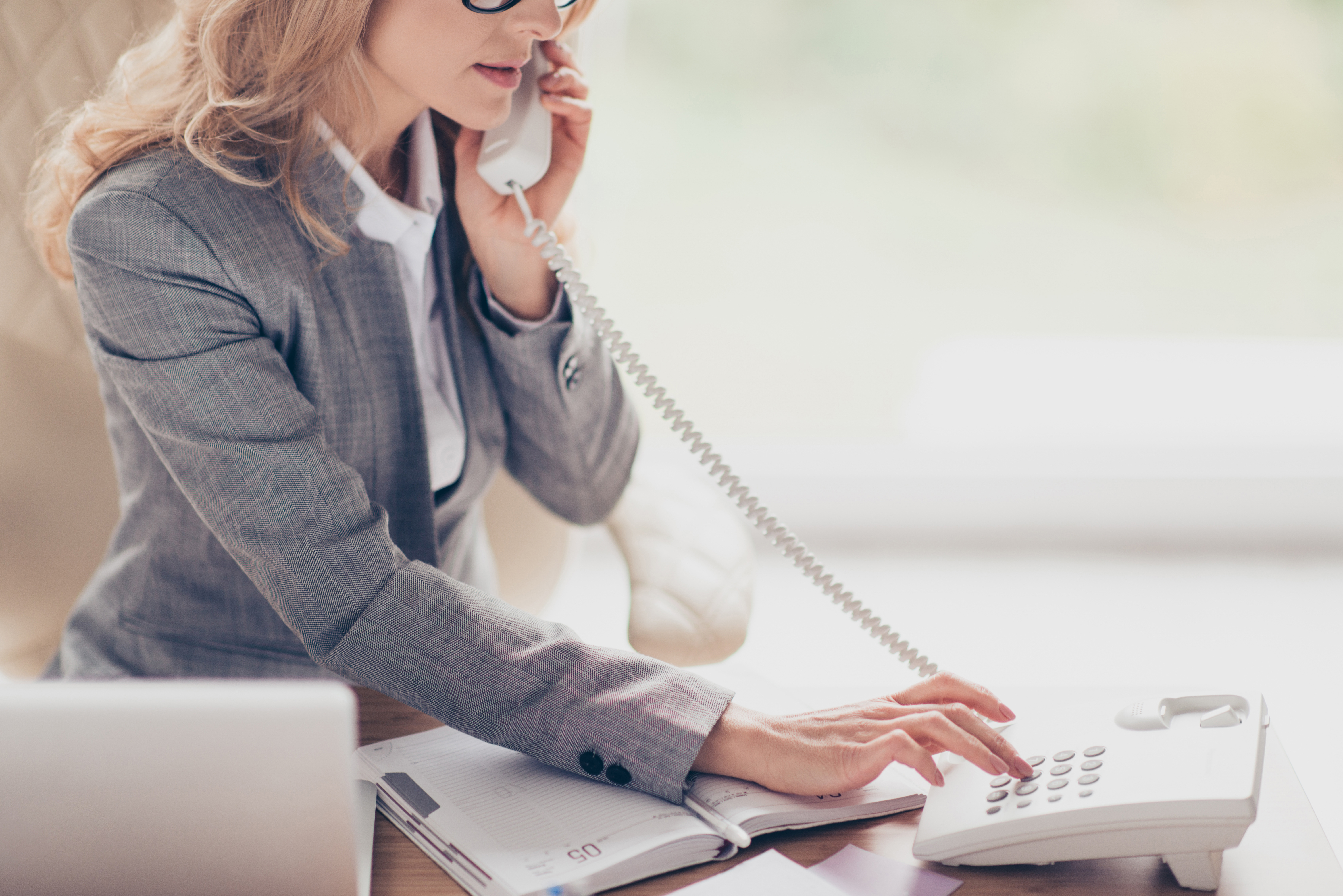A woman in a gray suit on the phone for individuals accessing services