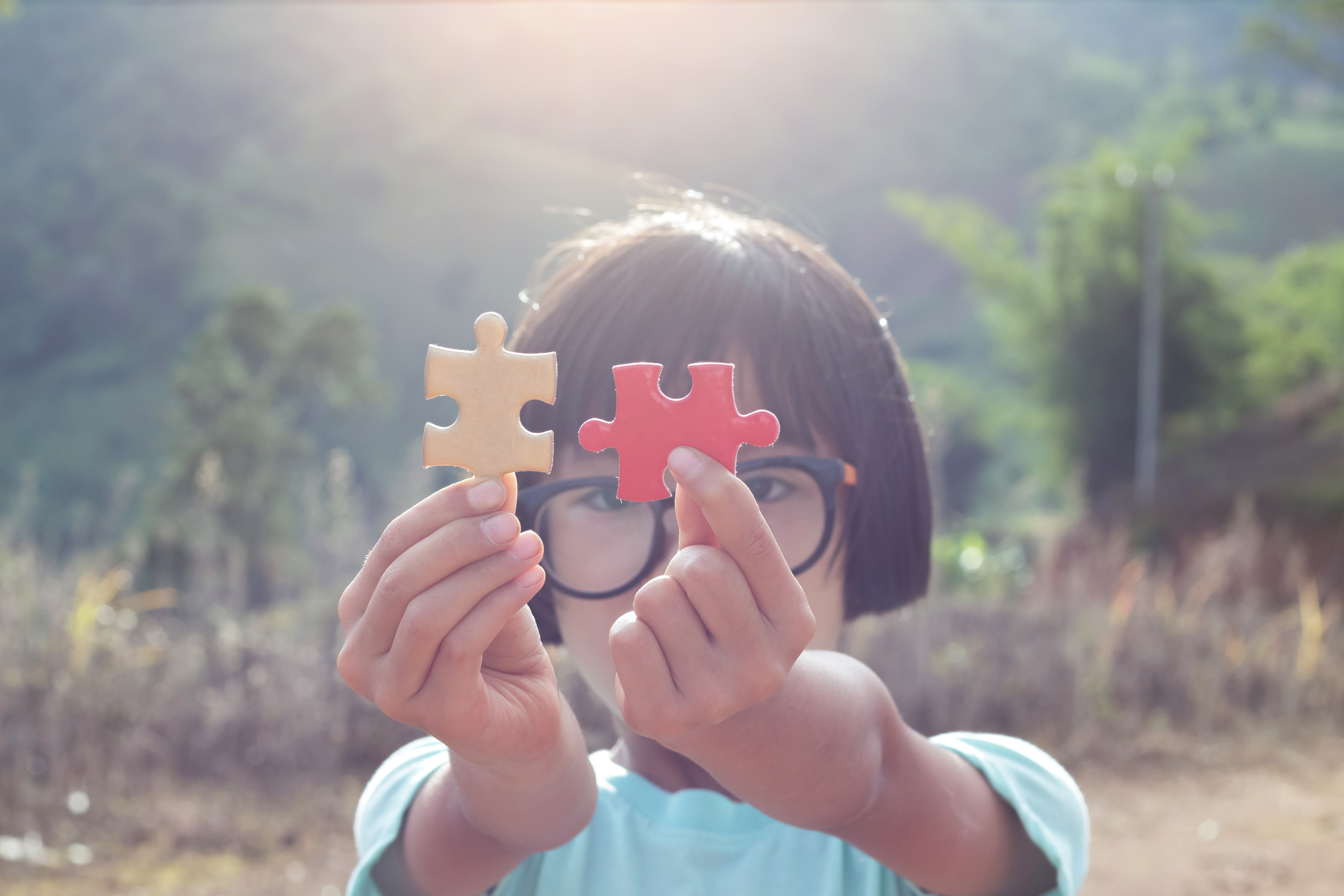 A kid holding up a red and yellow puzzle piece that goes together