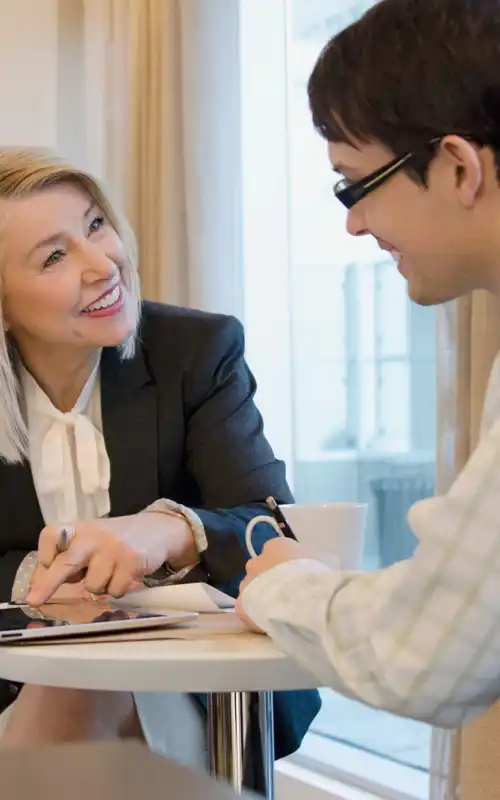A blonde woman leaning forward and smiling with a well-dressed man