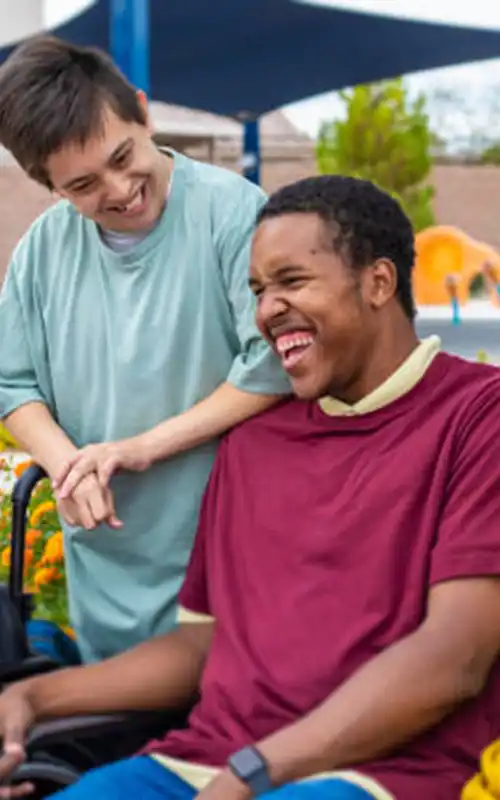 A diverse group of friends with disabilities smiling and laughing in a park