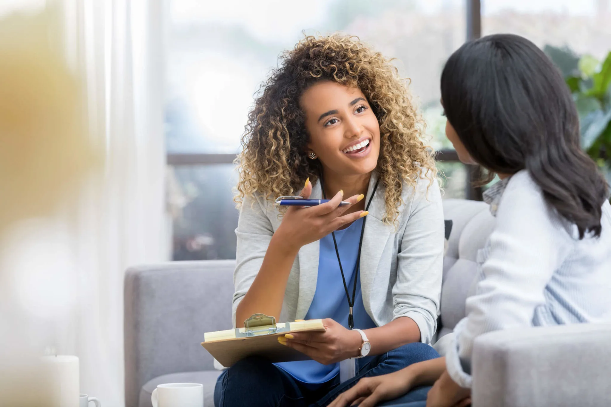 A mental health specialist with a brunette and blonde afro providing talk therapy and smiling