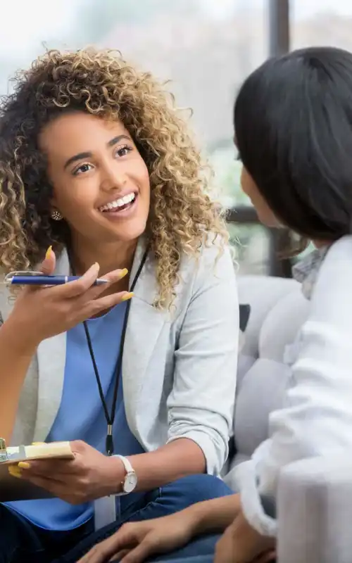 A mental health specialist with a brunette and blonde afro providing talk therapy and smiling