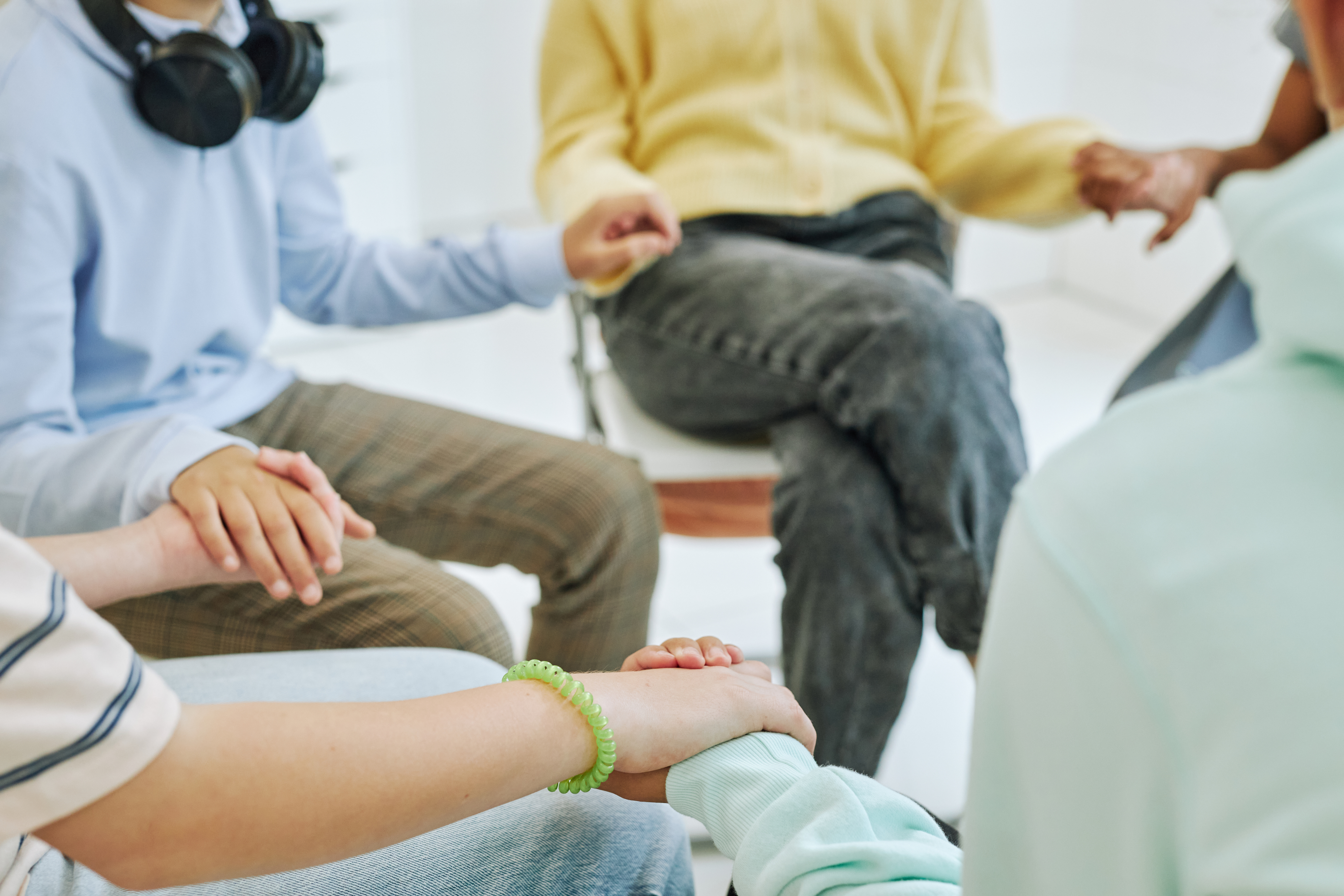 A group of people holding hands in a therapy group session