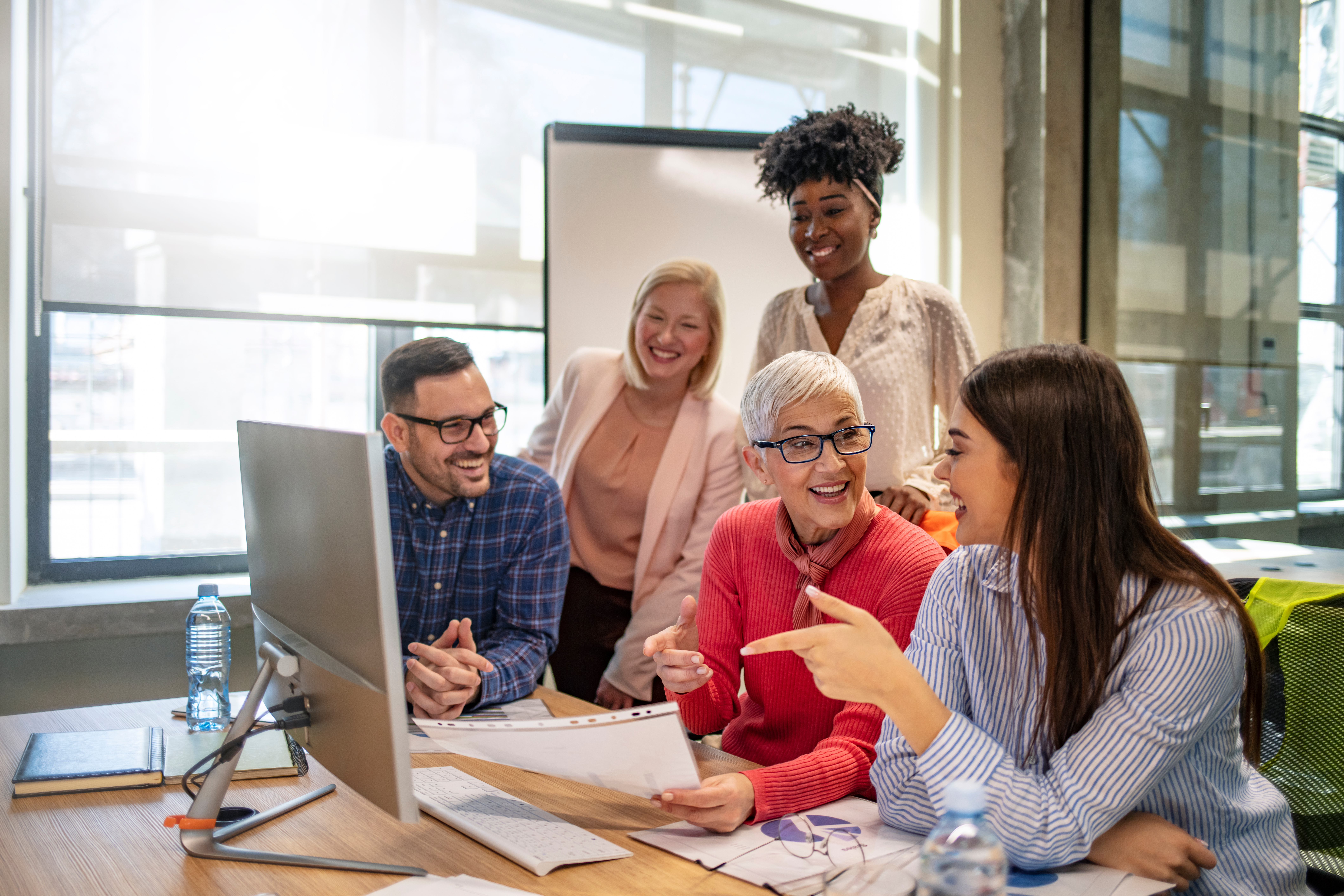Group of people conversing around a laptop regarding their careers