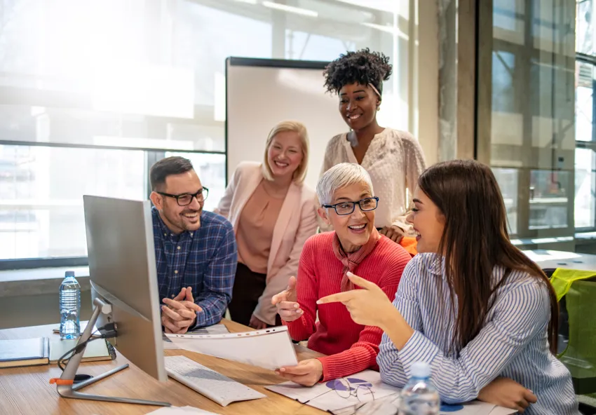 Group of people conversing around a laptop regarding their careers