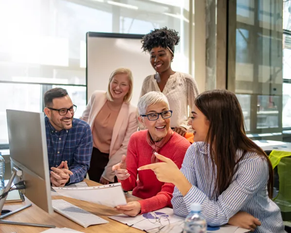 Group of people conversing around a laptop regarding their careers