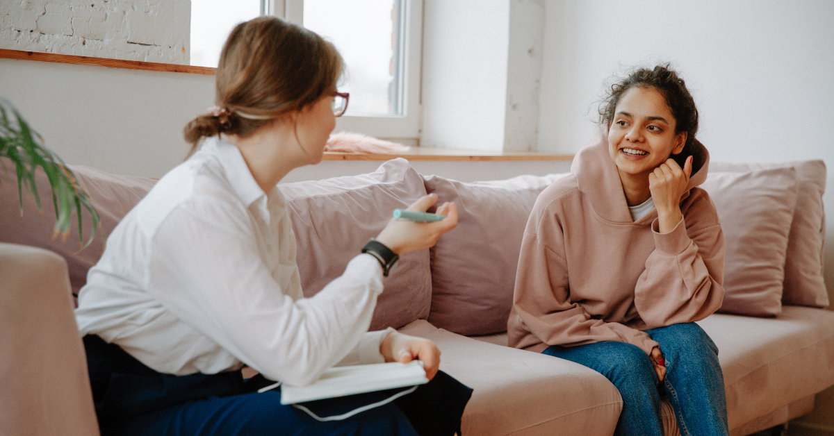 A therapist counseling a young girl with curly hair and in a brown sweatshirt