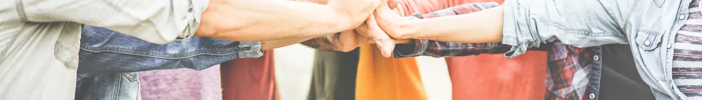 Group of smiling friends placing their hands together in a huddle