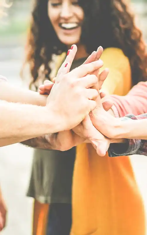 Group of smiling friends placing their hands together in a huddle